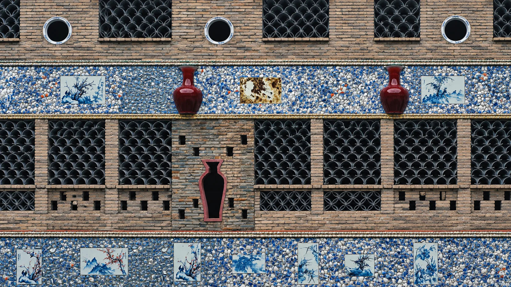 A Jingdezhen wall faced in porcelain shards, blue-and-white tiles and red vases set into the brickwork