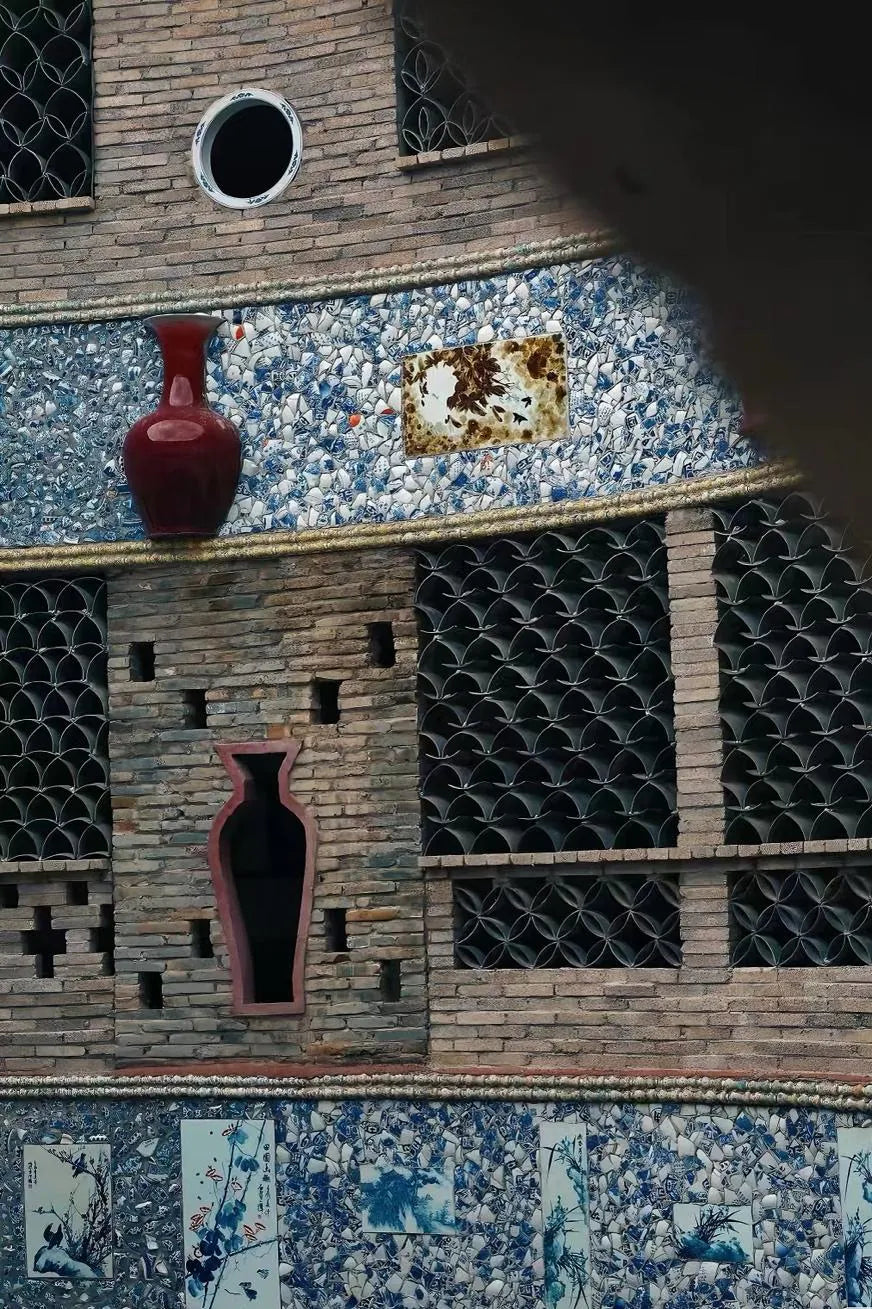 A Jingdezhen wall built from porcelain shards, stacked saggar rings and a red-glazed vase set into the brickwork