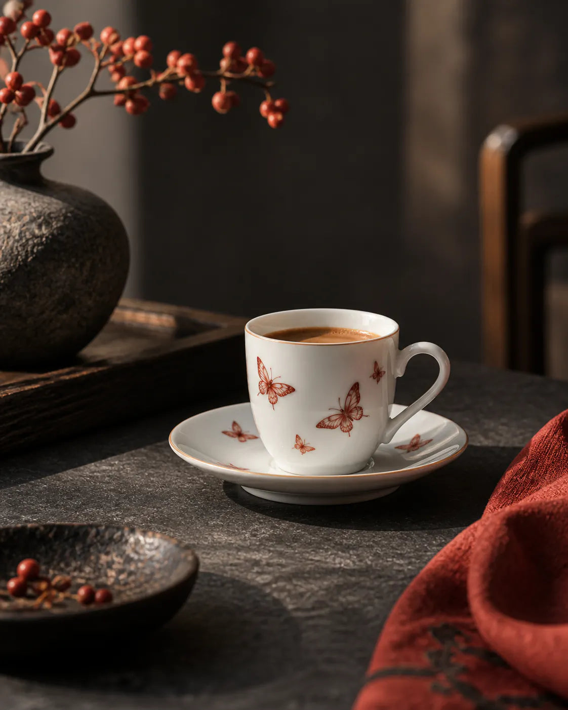 White cup and saucer with red butterflies in warm side light.